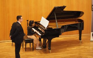 Klavierlehrer Marco Grilli aus Düsseldorf mit Schülerin bei Konzert auf Bühne